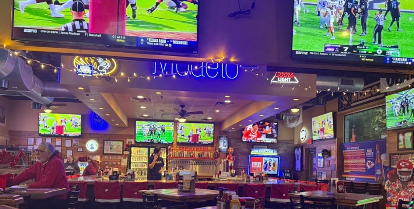 Bar top with tables, chairs and televisions showing sporting games